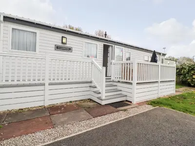 a white house with a porch and a white fence at Rosella 38 in Morecambe