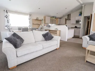 a living room with a white couch and a kitchen at Rosella 38 in Morecambe
