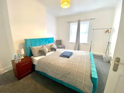 a bedroom with a bed with a blue headboard at Merseyside in Birkenhead