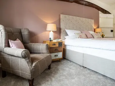 a bedroom with a bed and a chair at Longlands Farm Cottage in Grange Over Sands