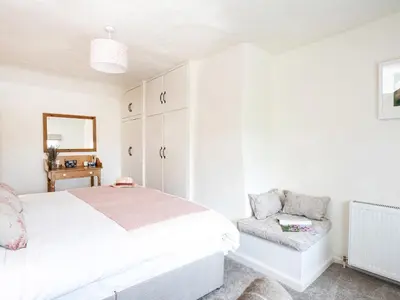 a white bedroom with a bed and a chair at Longlands Farm Cottage in Grange Over Sands
