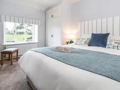 a bedroom with a large white bed with a blue blanket at Longlands Farm Cottage in Grange Over Sands