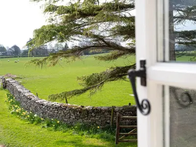 a stone wall with sheep in a field at Longlands Farm Cottage in Grange Over Sands