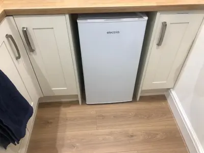 a white dishwasher in a kitchen under a counter at A secluded Garden Room in sunny Southport in Southport