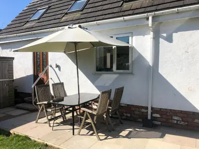 a table and chairs with an umbrella in front of a house at A secluded Garden Room in sunny Southport in Southport