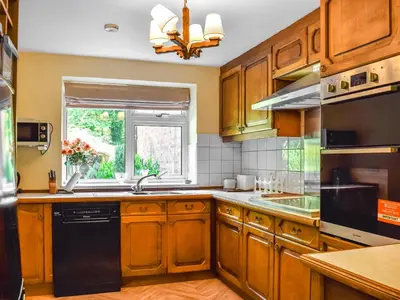 a kitchen with wooden cabinets and a window at Court House in Halsall