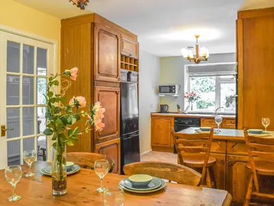 a kitchen with a table with a vase of flowers at Court House in Halsall