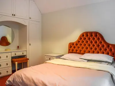 a bedroom with a bed with an orange headboard at Court House in Halsall