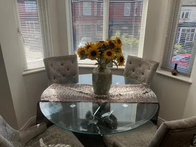 a glass table with a vase of sunflowers on it at Kensington Luxury Apartment on Gated Development in Leafy edge of Chorley Town Centre in Chorley