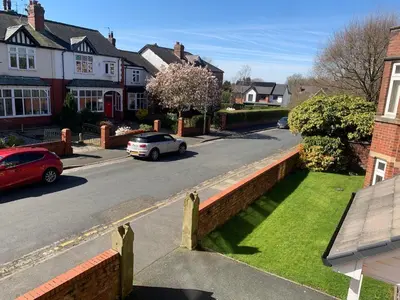 a city street with houses and a car on the road at Kensington Luxury Apartment on Gated Development in Leafy edge of Chorley Town Centre in Chorley