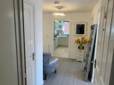 a hallway with a blue chair and a kitchen at Kensington Luxury Apartment on Gated Development in Leafy edge of Chorley Town Centre in Chorley