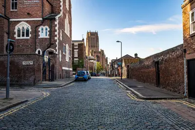 a cobblestone street with a blue car parked on the street at Host & Stay - The Coachouse at Pilgrim St in Liverpool
