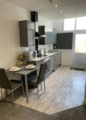 a large kitchen with a table and chairs in it at Newly Refurbished Clarendon Apartments, Free WIFI, Parking in Blackpool