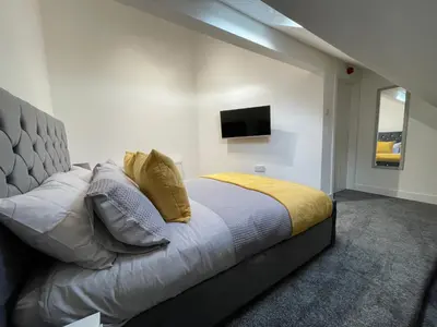 a bedroom with a bed and a television on the wall at Newly Refurbished Clarendon Apartments, Free WIFI, Parking in Blackpool