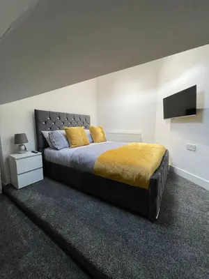 a bedroom with a large bed with a yellow blanket at Newly Refurbished Clarendon Apartments, Free WIFI, Parking in Blackpool