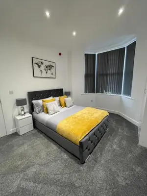 a bedroom with a large bed with a yellow blanket at Newly Refurbished Clarendon Apartments, Free WIFI, Parking in Blackpool