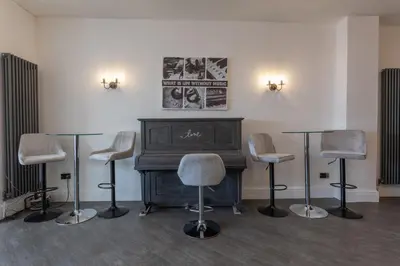 a room with a piano and four chairs and tables at RESIDENCY LUXURY SEAFRONT HOTEL in Blackpool