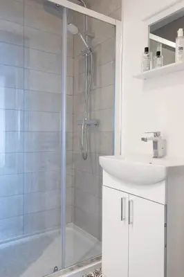 a white bathroom with a shower and a sink at RESIDENCY LUXURY SEAFRONT HOTEL in Blackpool