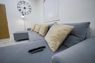 a blue couch with two pillows and a remote control at Cozy Charming Bungalow BRAND NEW in Preston