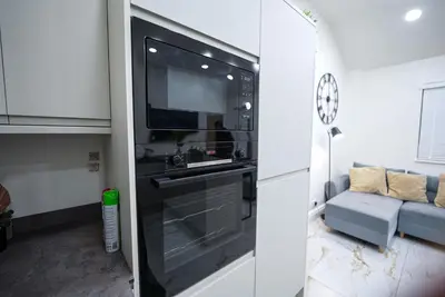 a kitchen with a black oven and a couch at Cozy Charming Bungalow BRAND NEW in Preston