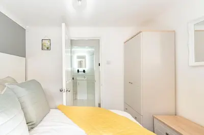 a white bedroom with a bed and a closet at 1 The Cottage in Upholland