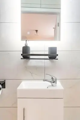 a white bathroom with a sink and a mirror at 1 The Cottage in Upholland