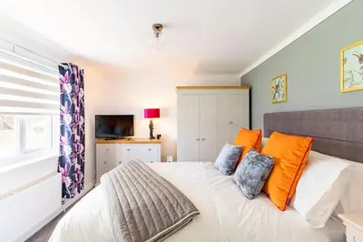 a bedroom with a large white bed with orange pillows at 1 The Cottage in Upholland
