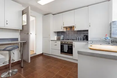 a kitchen with white cabinets and a counter top at Flatzy - Sleeps 16 Near Football Ground & Ping Pong Table in Liverpool