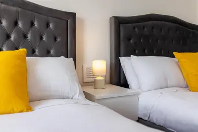 a bedroom with two beds and a lamp on a night stand at Flatzy - Sleeps 16 Near Football Ground & Ping Pong Table in Liverpool