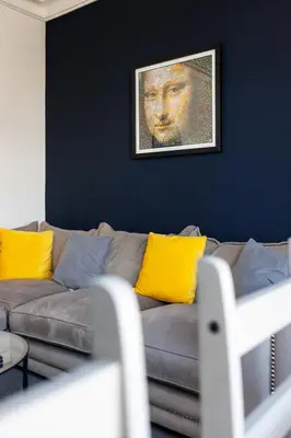 a living room with a gray couch with yellow pillows at Flatzy - Sleeps 16 Near Football Ground & Ping Pong Table in Liverpool