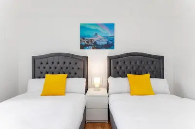 two beds in a room with white and yellow pillows at Flatzy - Sleeps 16 Near Football Ground & Ping Pong Table in Liverpool