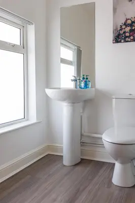 a white bathroom with a sink and a toilet at Flatzy - Sleeps 16 Near Football Ground & Ping Pong Table in Liverpool