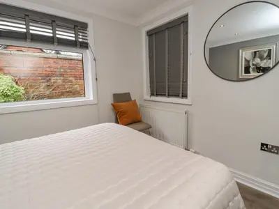 a bedroom with a white bed and a mirror at Jasmine Cottage in Lytham St Annes