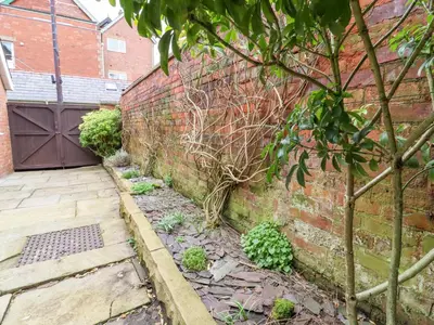 a brick wall with a gate and a tree at Jasmine Cottage in Lytham St Annes