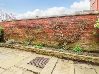 a brick wall with plants on the side of it at Jasmine Cottage in Lytham St Annes