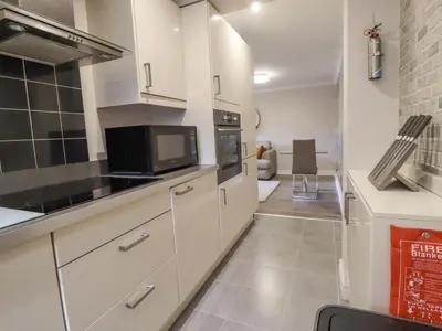 a kitchen with white cabinets and a microwave at Jasmine Cottage in Lytham St Annes