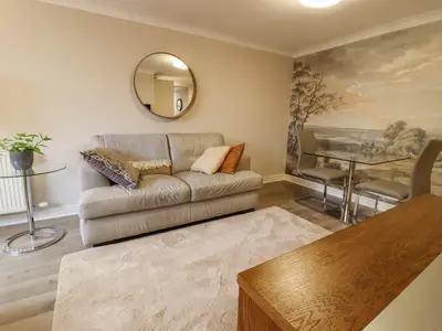 a living room with a couch and a mirror at Jasmine Cottage in Lytham St Annes