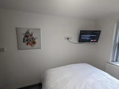 a bedroom with a bed and a tv on the wall at Station Apartments in Ashton in Makerfield
