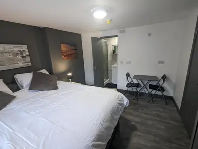 a bedroom with a bed and a table and chairs at Station Apartments in Ashton in Makerfield