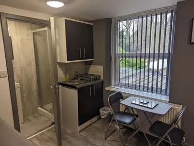 a small kitchen with a table and chairs and a window at Station Apartments in Ashton in Makerfield