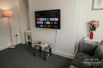 a living room with a couch and a tv on the wall at Dover St by Prestige Properties SA in Barrow in Furness