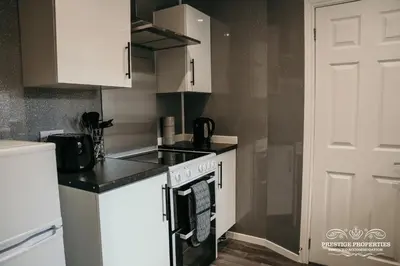 a kitchen with white cabinets and a stove top oven at Dover St by Prestige Properties SA in Barrow in Furness