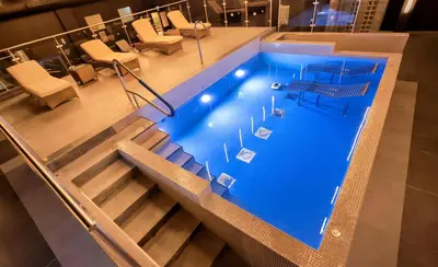 a swimming pool with stairs and chairs in a building at Park hall Hotel & Spa Lancashire, a member of Radisson Individuals in Eccleston
