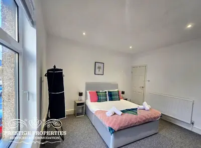 a bedroom with a bed and a large window at Warwick St by Prestige Properties SA in Barrow in Furness