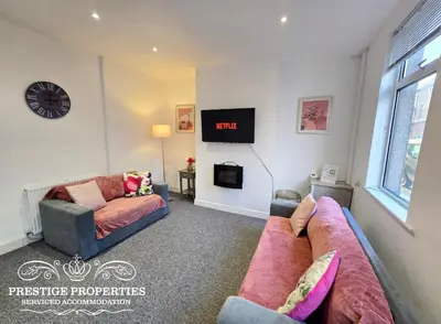 a living room with a couch and a clock on the wall at Warwick St by Prestige Properties SA in Barrow in Furness