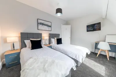 a bedroom with two beds and a desk with a chair at Stylish Luxury Large 4BR KingBed in Barrow in Furness