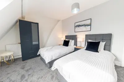 a bedroom with two beds and a blue cabinet at Stylish Luxury Large 4BR KingBed in Barrow in Furness