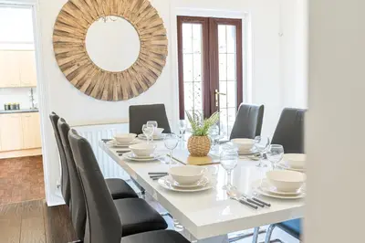 a dining room with a table with chairs and a mirror at Stylish Luxury Large 4BR KingBed in Barrow in Furness