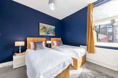 two beds in a bedroom with blue walls and a window at Stylish Luxury Large 4BR KingBed in Barrow in Furness