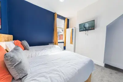 a bedroom with two beds and a blue wall at Stylish Luxury Large 4BR KingBed in Barrow in Furness